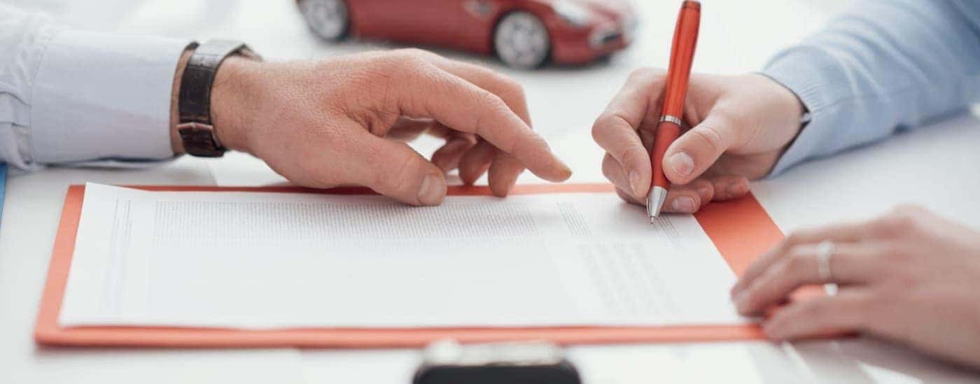 A salesman is pointing to where the buyer needs to sign on a loan.