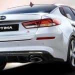 A white 2020 Kia Optima is shown from the rear driving on a track near Freehold, NJ.