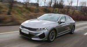 A gray 2021 Kia Optima driving on a rural road.