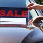A For Sale sign is being placed on the windshield of a used car in Philadelphia.