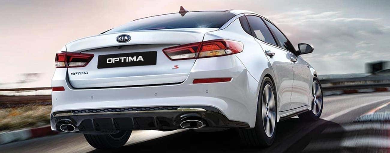 A white 2020 Kia Optima is driving on a highway near Freehold, NJ.