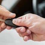 A close up is shown of a car key being handed over at an end of lease turn-in.