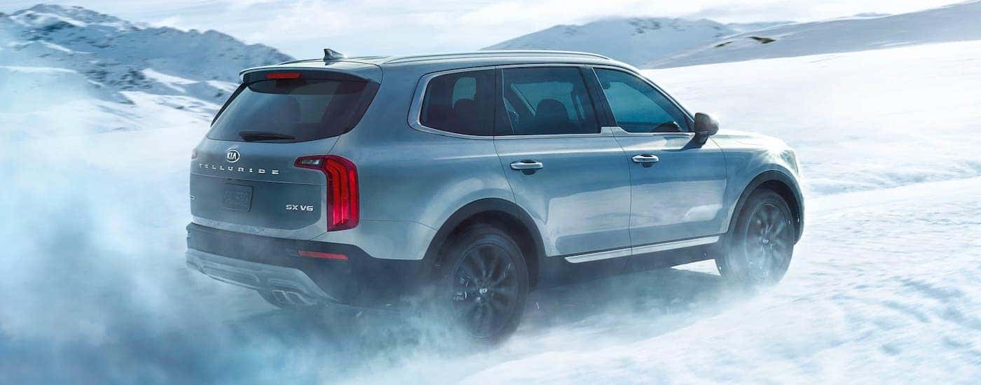 A silver 2021 Kia Telluride is driving in the snow after winning the 2021 Kia Telluride vs 2020 Ford Explorer comparison.