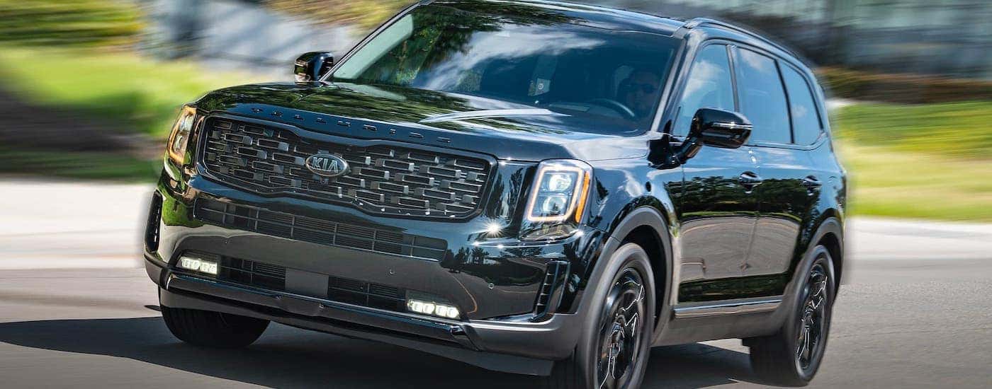 A black 2021 Kia Telluride is driving on a street near Freehold, NJ.