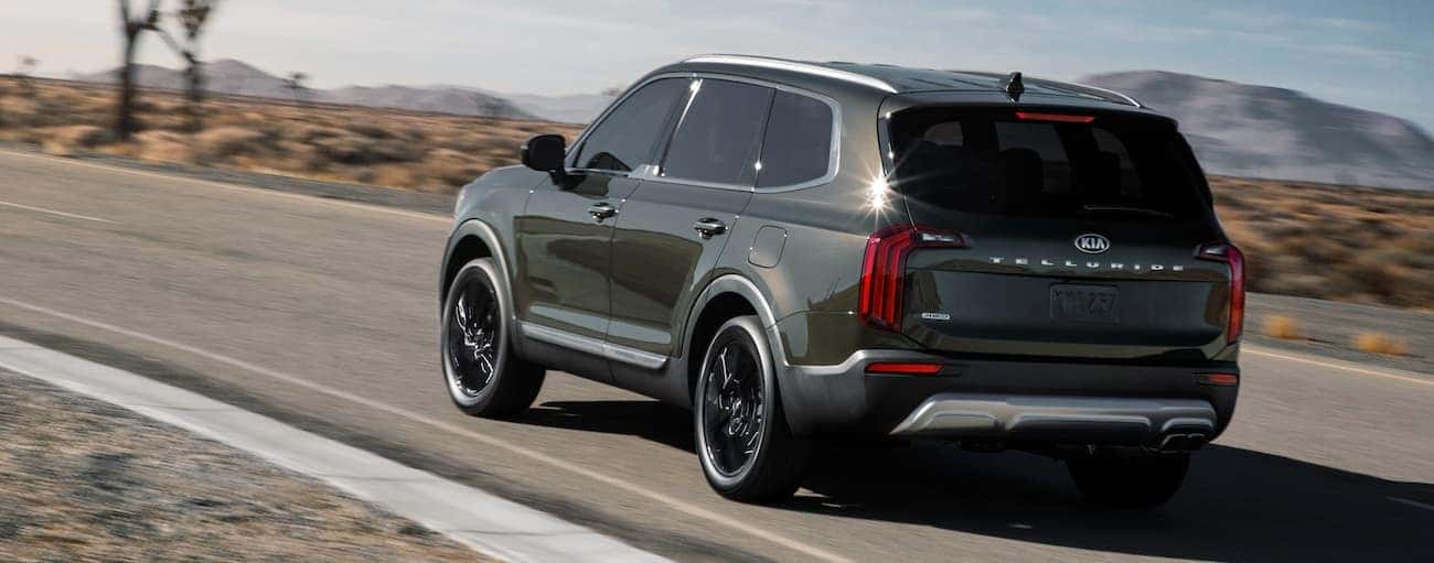 A dark green 2021 Kia Telluride is driving on a desert road after winning the 2021 Kia Telluride vs 2021 Toyota Highlander comparison.
