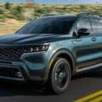 A dark green 2021 Kia Sorento is driving down the highway after leaving the Kia dealership.