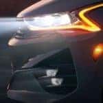 A closeup shows a headlight on a 2021 Kia K5 from the side at dusk.