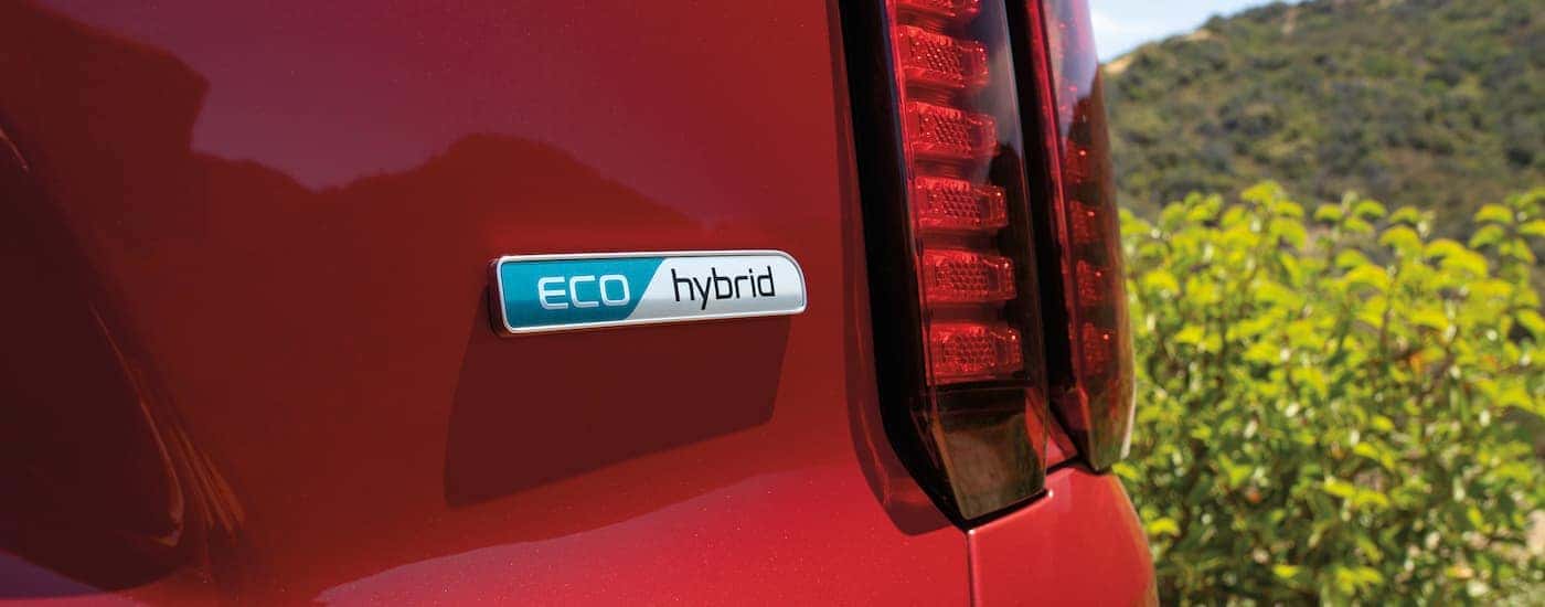 A close up shows the 'ECO hybrid' badge on a red 2022 Kia Sorento Hybrid.