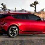 A red 2023 Kia EV6 for sale is shown parked on a desert road.