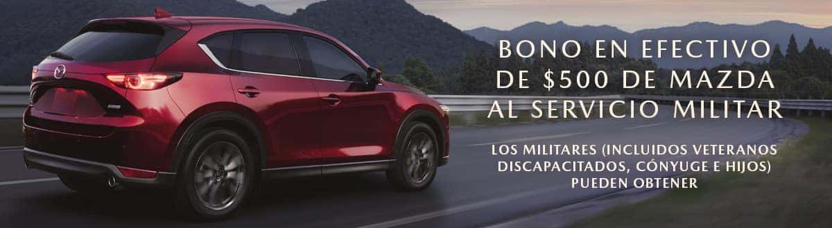 Red Mazda CX-5 on the left is driving into the sunset. The words 'BONO EN EFECTIVO DE $500 DE MAZDA AL SERVICIO MILITAR' and 'Los militares (incluidos veteranos discapacitados, cónyuge e hijos) pueden obtener' appears on the right. Sport Mazda Orlando, FL
