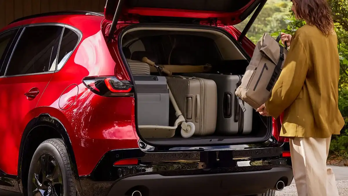 Cargo area of a 2026 Mazda CX-5 loaded with two large checked bags and two carry-on suitcases behind the upright rear seats at Sport Mazda South in Orlando, Florida