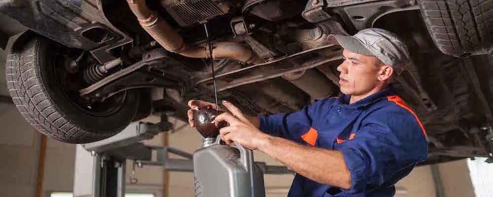 Car mechanic draining motor oil under lifted car