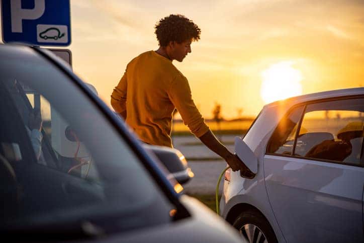 A man charging his electric car at a public charging station