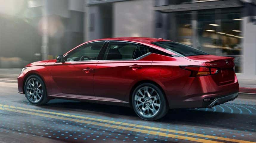 Red Nissan Sedan driving on the city streets
