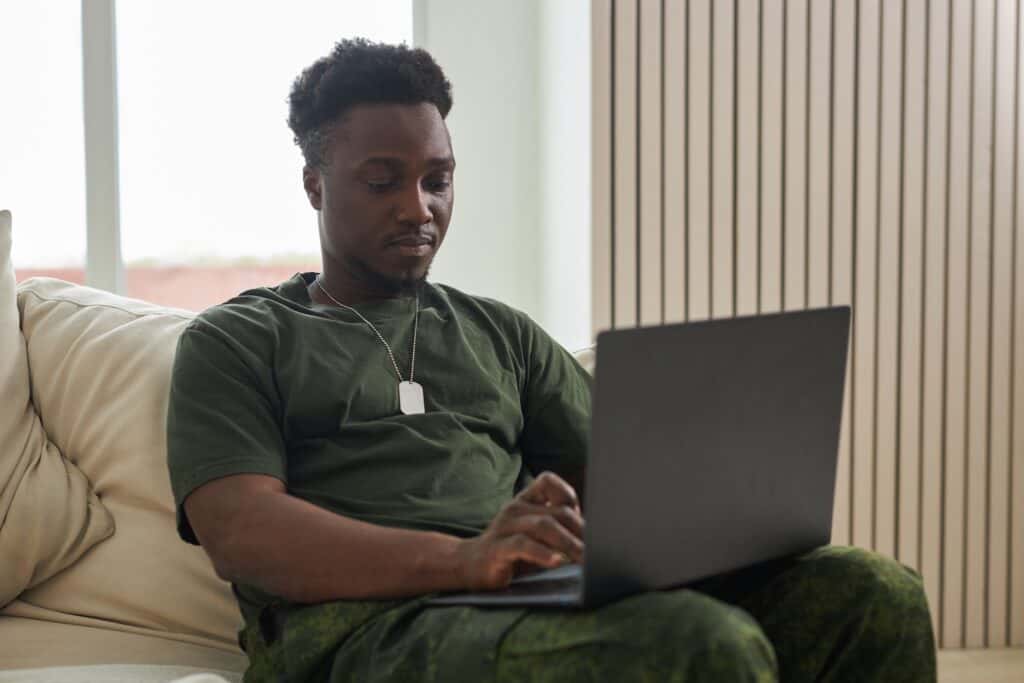 African American soldier using laptop while sitting on sofa at home