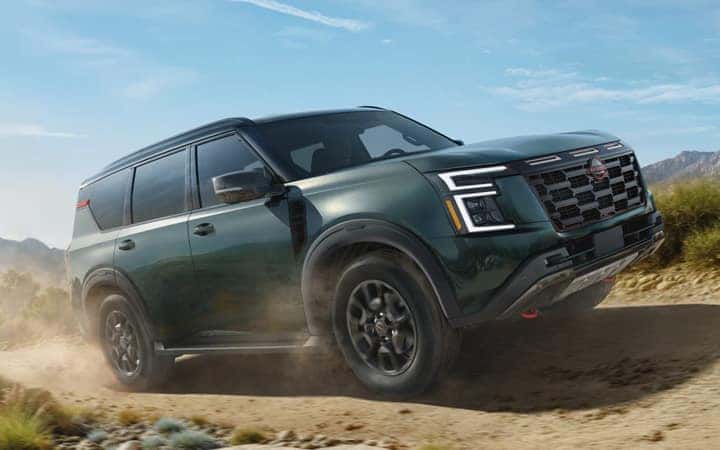 Turqoise Nissan SUV driving on dirt road