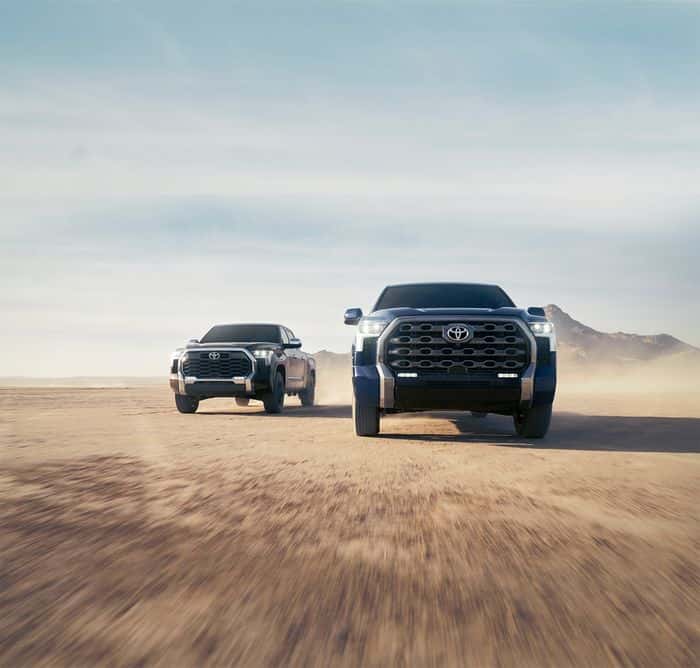 Tundra trucks driving on an open desert road