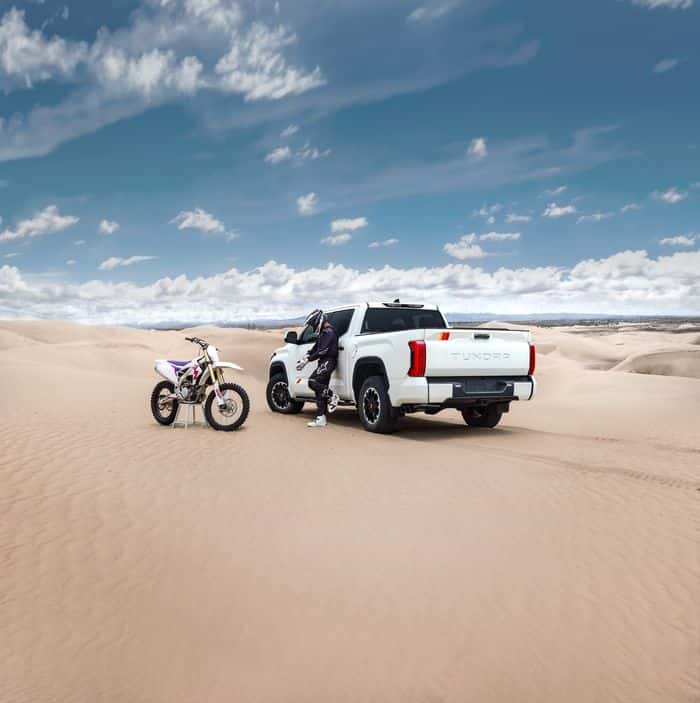 Toyota Tundra beside a dirt bike in the dunes