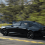 black 2023 Honda Accord Hybrid driving on highway with lake and mountain in background