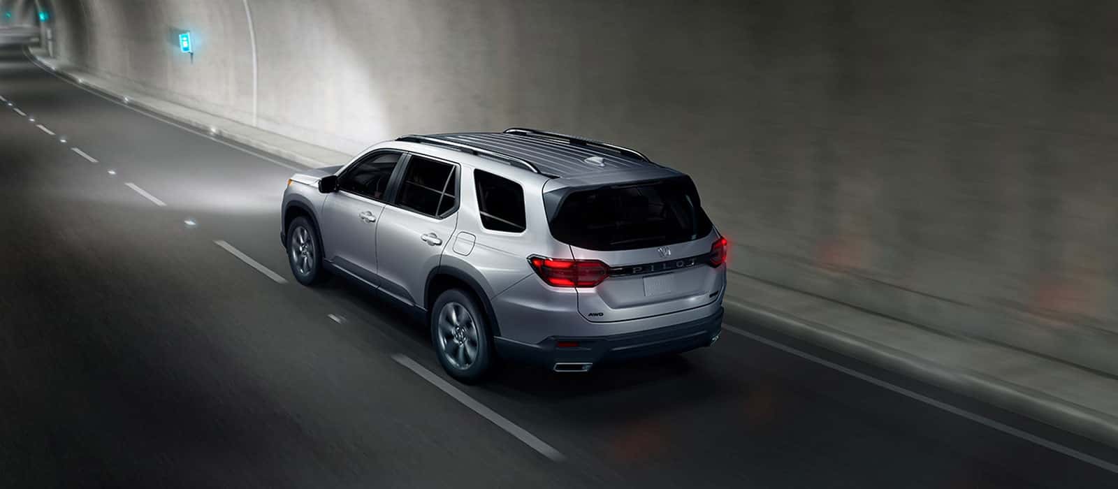 A silver Honda Pilot driving through a tunnel.