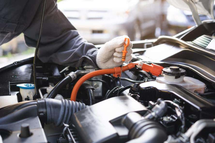 A technician working on a vehicle's repairs under the hood.