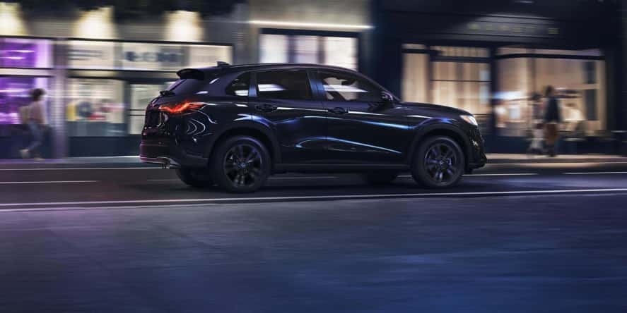 A blue Honda HR-V driving at night through a city.