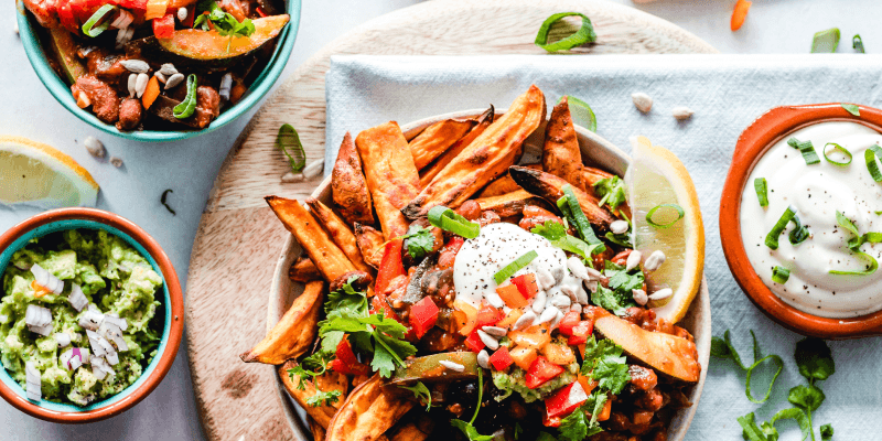 Four colorful vegan dishes in ceramic bowls and plates on a table