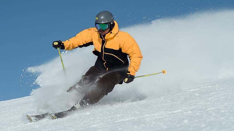 person in yellow jacket skiing down mountain