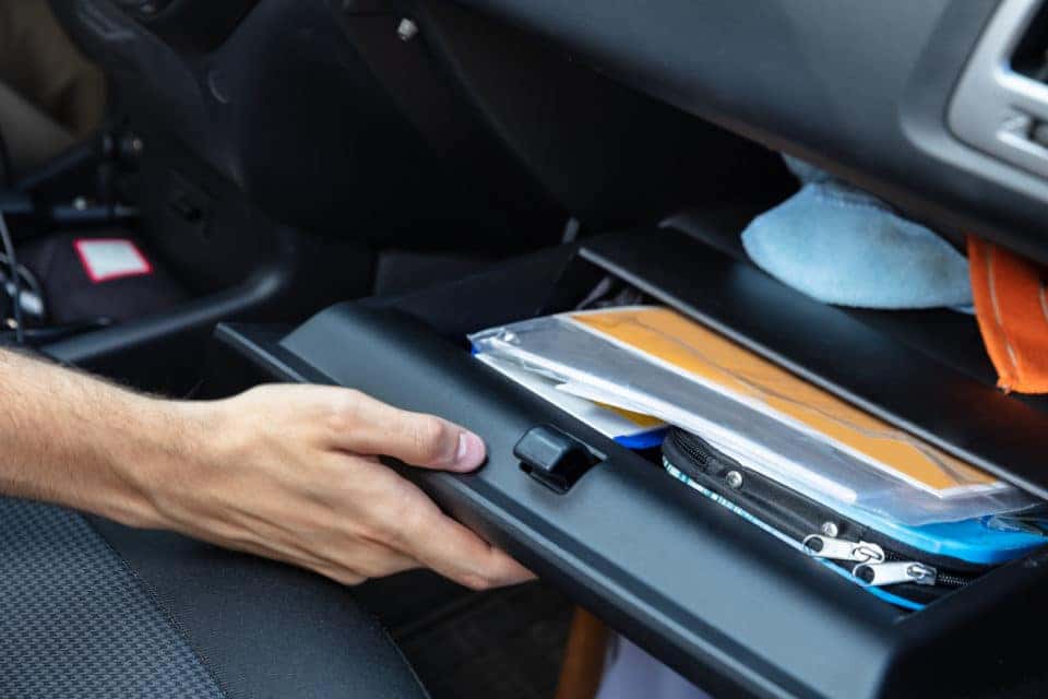 A hand opening a glove box inside a vehicle