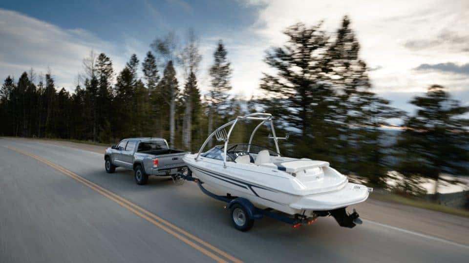 Silver Toyota Tacoma towing a boat along a highway