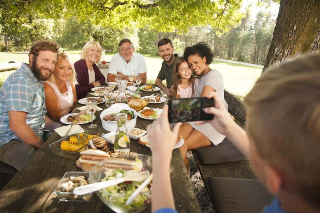 child taking photo of family at outdoor dinner table