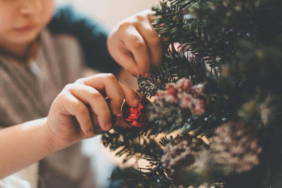 A boy hanging ornaments on a Christmas tree