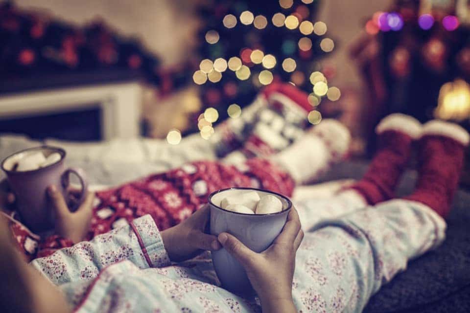 Kids in Christmas pajamas holding cups of hot chocolate 