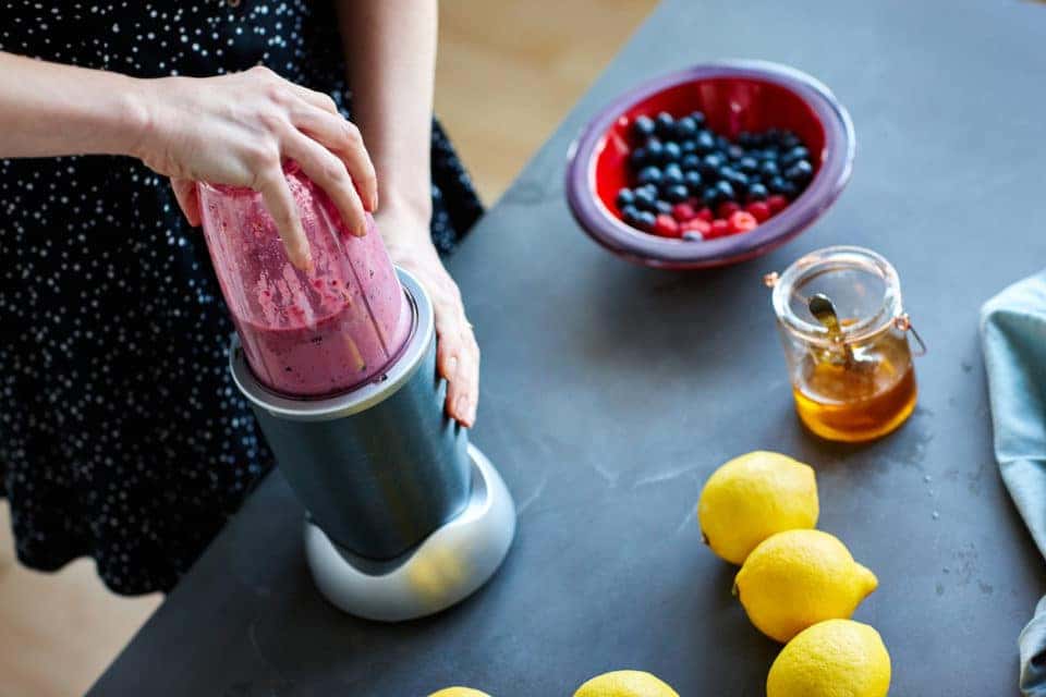 Close up of a person making a smoothie using a bldender at home in kitchen