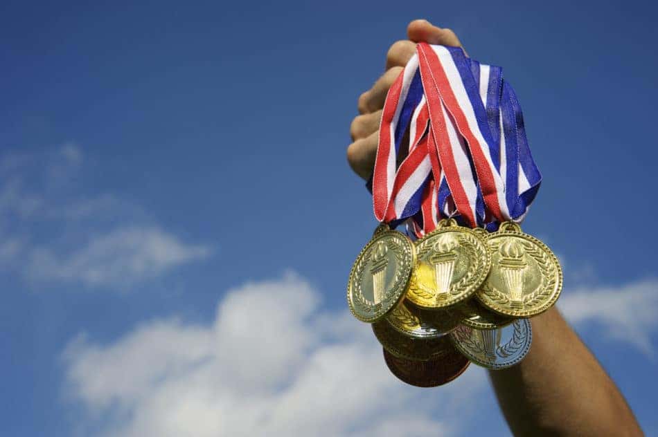 Hand holds up a bunch of gold, silver, and bronze medals