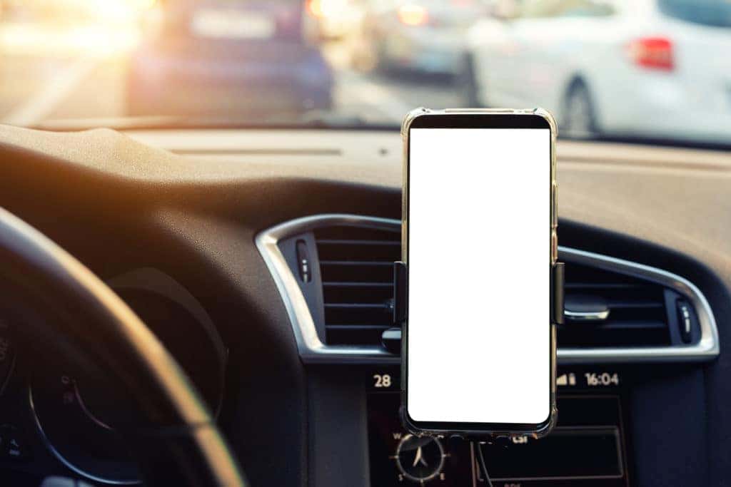 white screen of smartphone mounted on car's dashboard