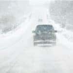 An SUV is driving on a highway in Milwaukee, WI, during a snow storm.